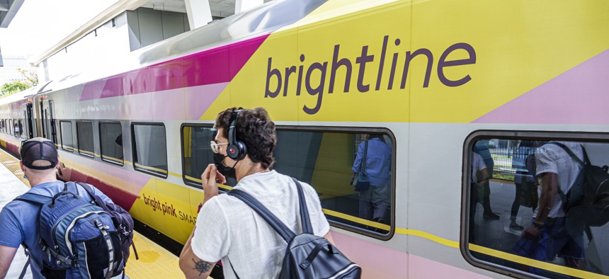 Arriving passengers are seen on a platform in West Palm Beach, Florida, next to a Brightline passenger train. 