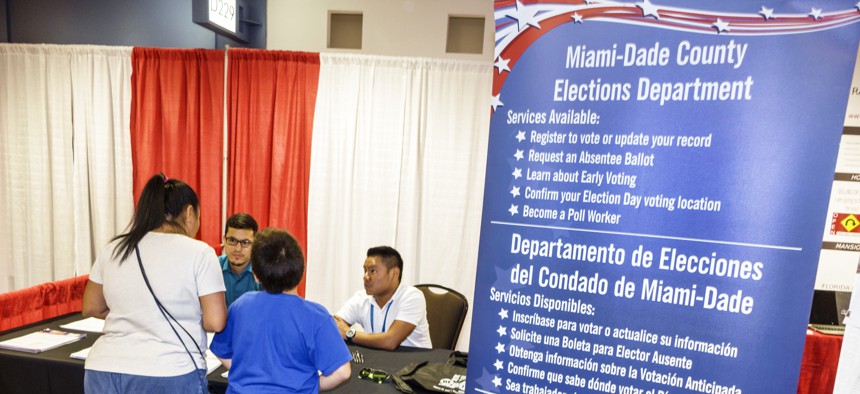 In this undated photo, staff of the Miami-Dade County Elections Department help register voters at the International Auto Show at the Miami Beach Convention Center.