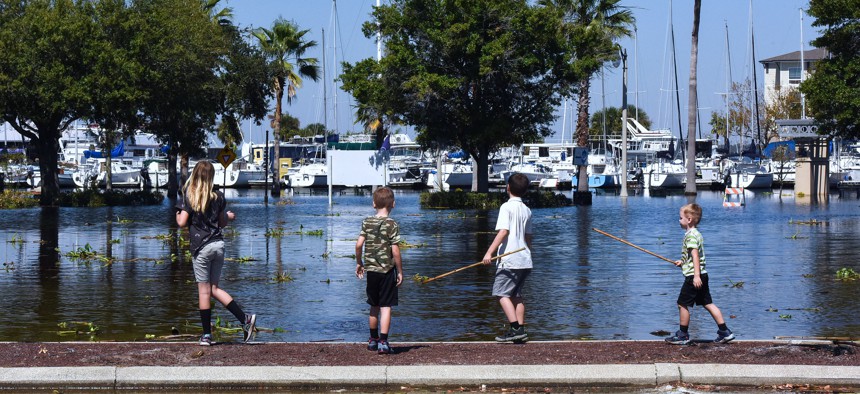 Children play Oct. 9 in a flooded parking lot near the Sanford Riverwalk as the St. Johns River reaches major flood stage, causing Lake Monroe to breach the sea wall in the aftermath of Hurricane Ian in downtown Sanford. 
