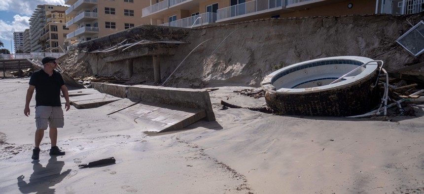 A man walks past a collapsed wall and pool of a beachfront apartment building in the aftermath of Hurricane Nicole in Daytona Beach, Nov. 11, 2022.