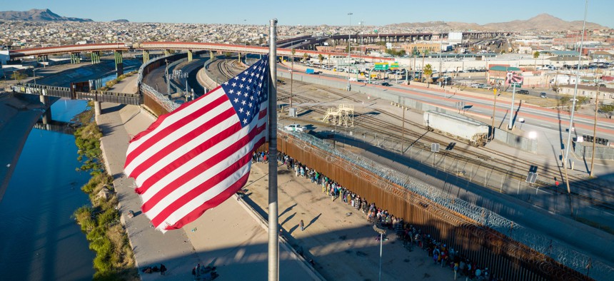 An aerial view of the American flag flying over an international bridge as immigrants line up next to the U.S.-Mexico border fence to seek asylum on December 22, 2022 in El Paso, Texas. 