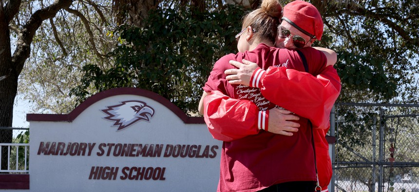 Iris Diaz hugs Mark Muniz from the Guardian Angels as she visits a memorial February 14, 2022 in front of Marjory Stoneman Douglas High School to honor those killed during a mass shooting in Parkland, Florida, in 2018. Fourteen students and three staff members were killed in a shooting at the school.