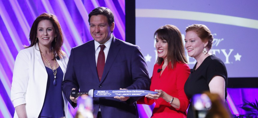 Moms for Liberty founders Tiffany Justice (left) and Tina Descovich present the Liberty Sword to Gov. Ron DeSantis before he speaks during the inaugural Moms For Liberty Summit at the Tampa Marriott Water Street on July 15, 2022 in Tampa. 