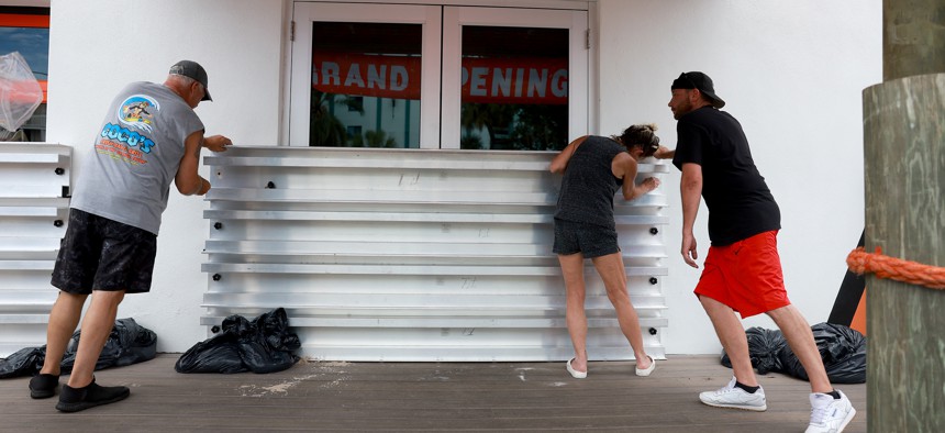 Steve Leitgeb, Michelle Fedeles, and Brandon Hadley place protective shutters over the openings at Coco's Crush Bar & Grill before the possible arrival of Hurricane Idalia on Aug. 29, 2023 in Indian Rocks Beach. Hurricane Idalia is forecast to make landfall on the Gulf Coast of Florida Wednesday morning. 