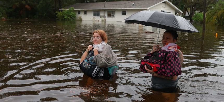 Makatla Ritchter (at left), and her mother, Keiphra Line, wade through flood waters after having to evacuate their home when the flood waters from Hurricane Idalia inundated it Aug. 30, 2023 in Tarpon Springs.